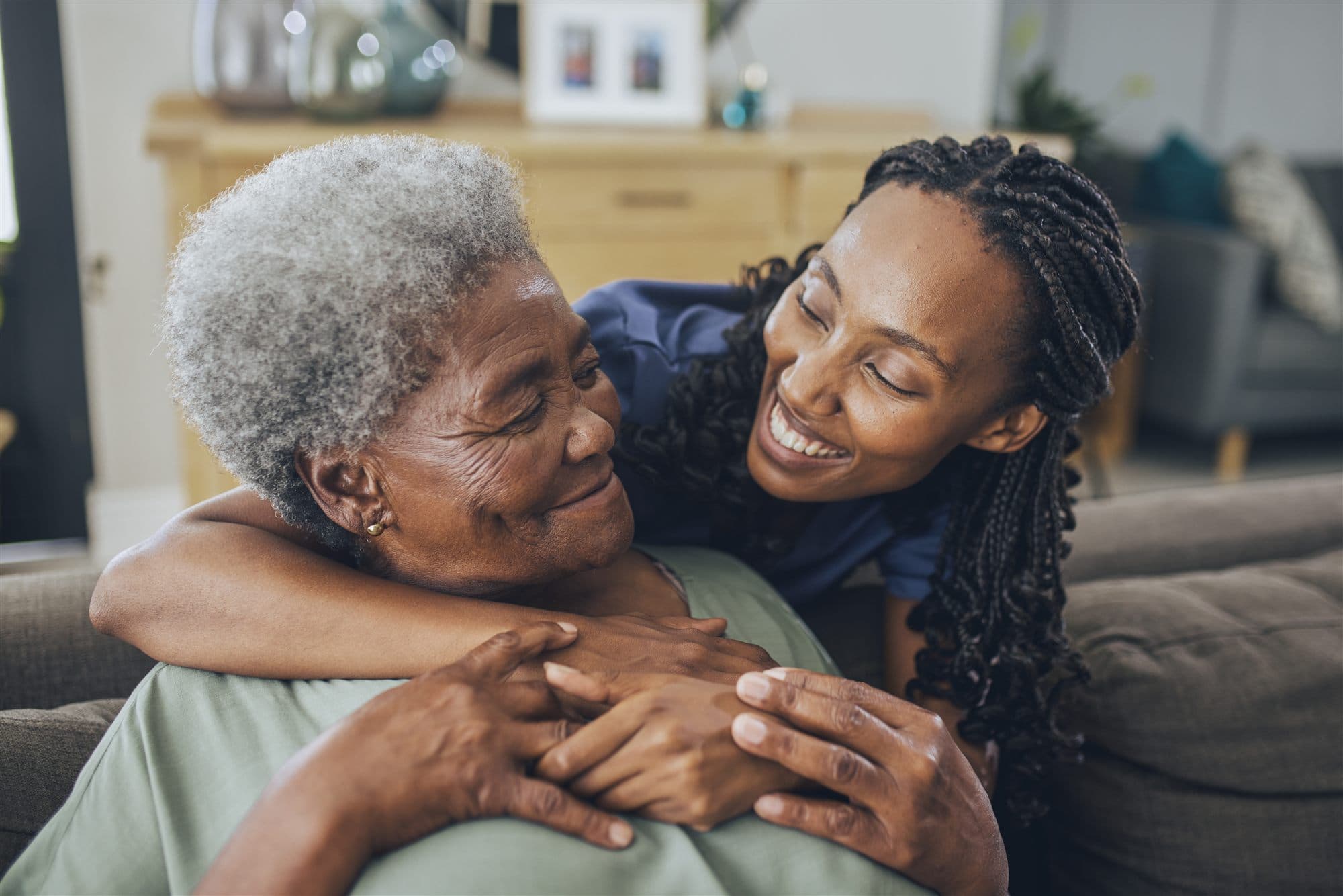 A caregiver and an older adult sharing a warm moment at home