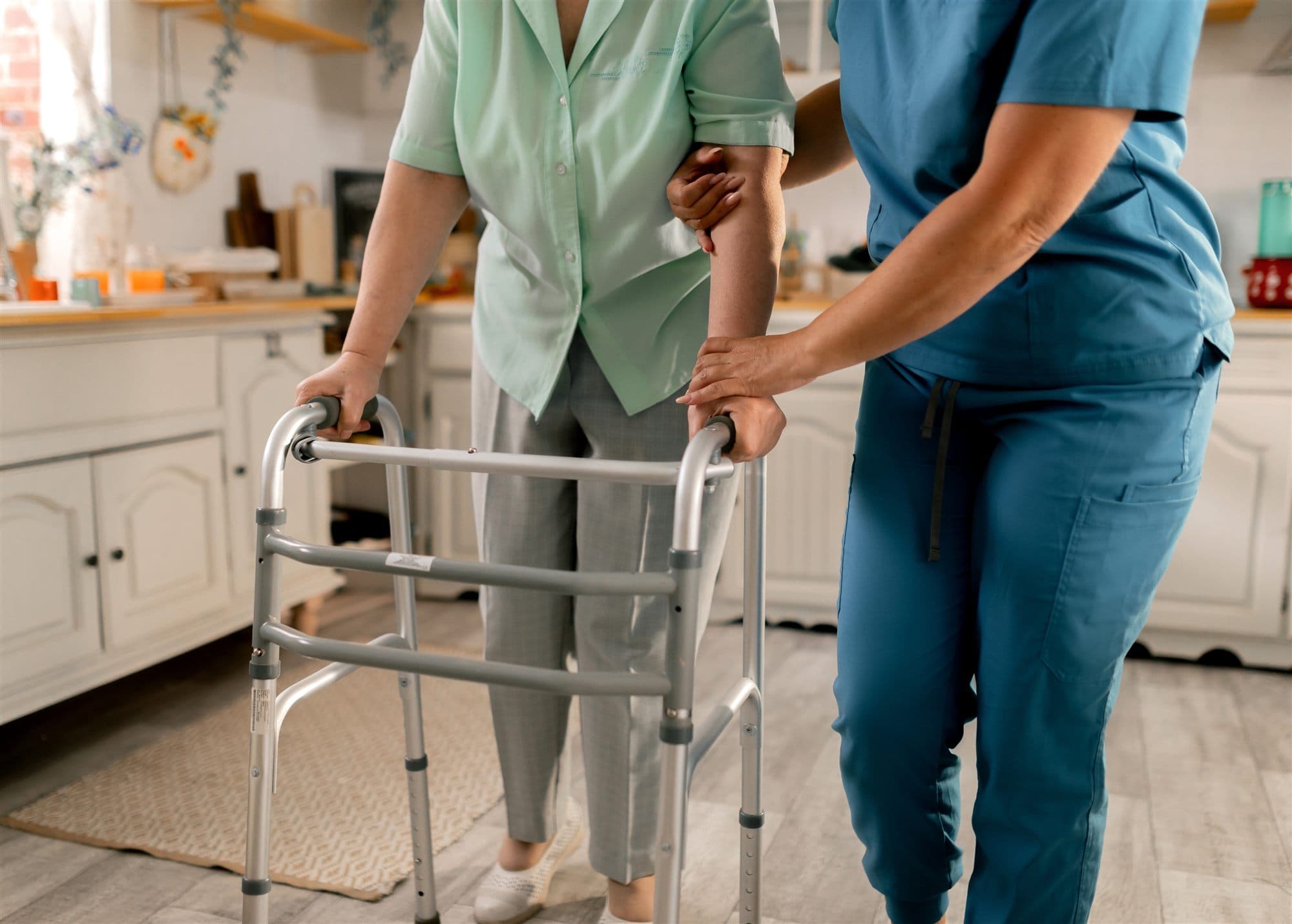 A nurse helping a patient walk with a walker after surgery