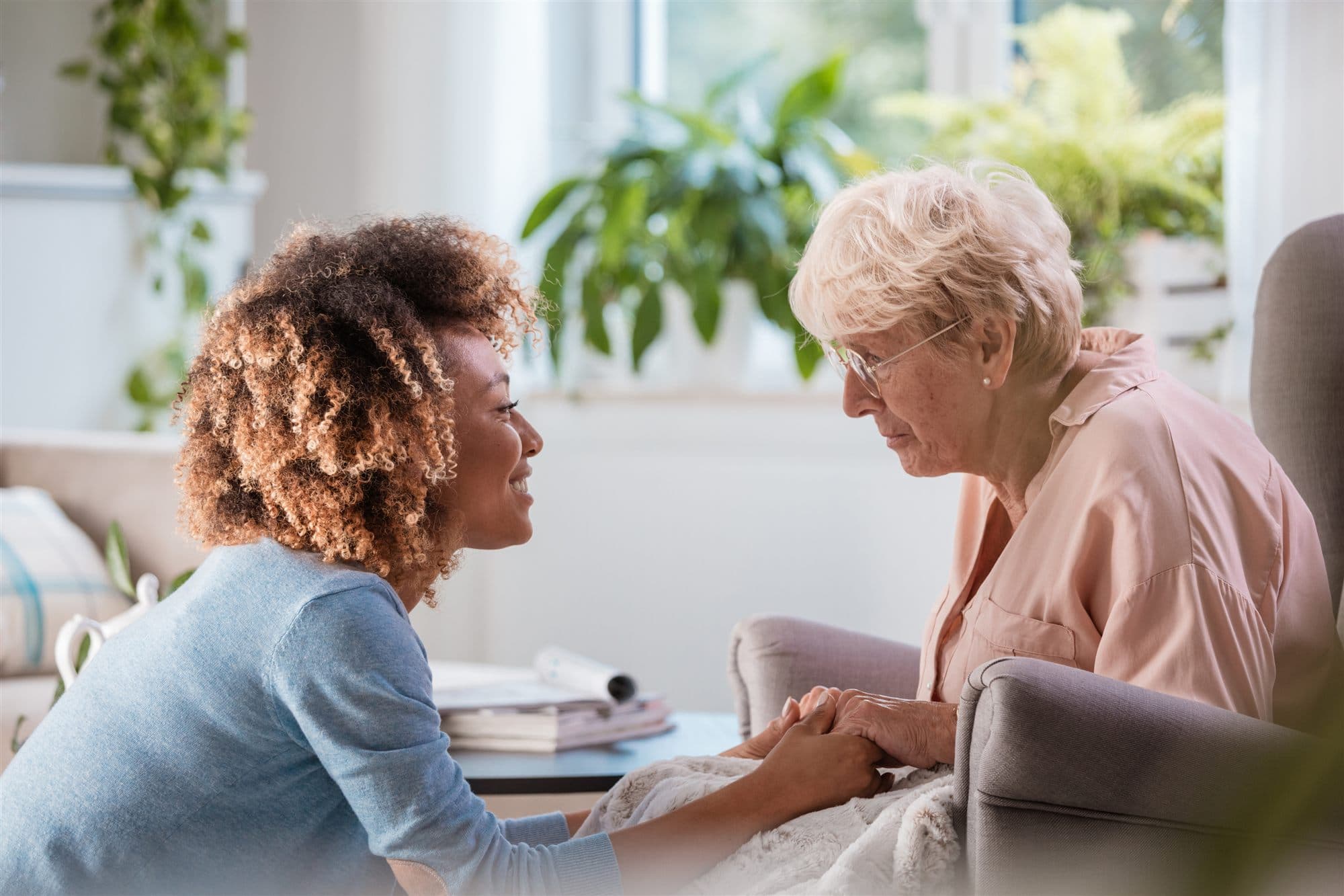 A caregiver holding hands with an older adult, sharing a warm, attentive conversation