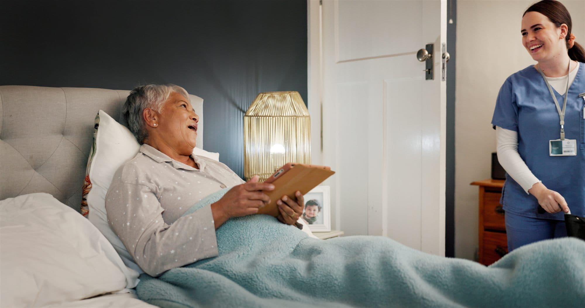 A caregiver checking in on an older adult in bed during an evening visit