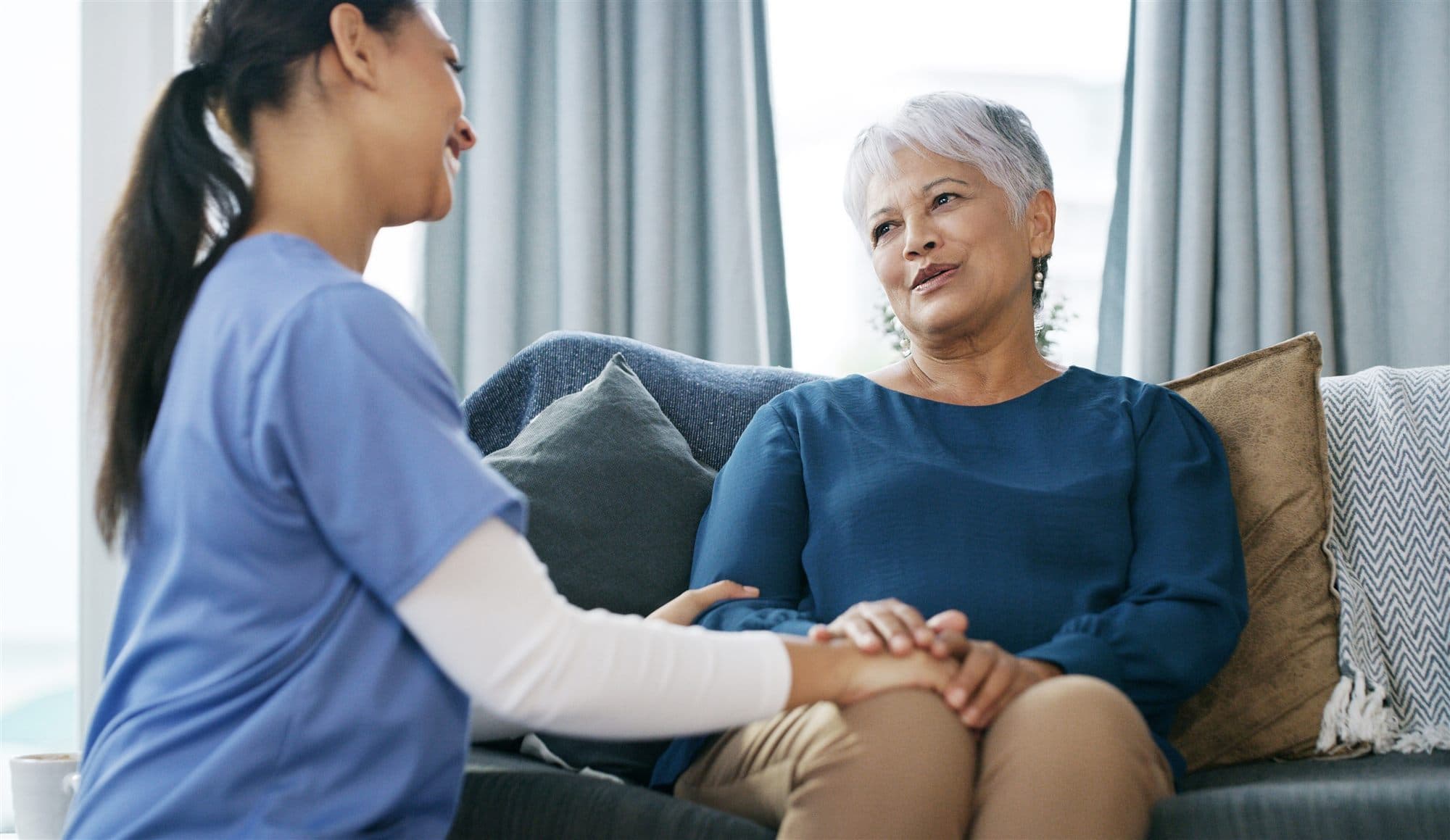 A caregiver holding hands with an older adult during a warm conversation