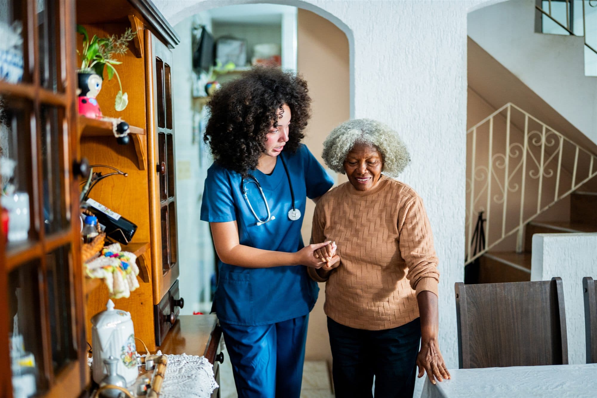 A caregiver walking hand-in-hand with an older adult at home
